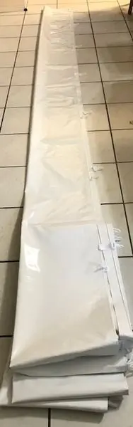 Long white folded curtain on tiled floor.