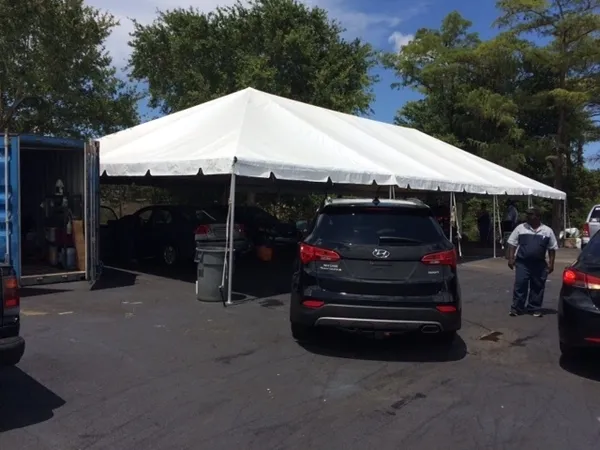 Vehicles sheltered beneath a white tent.
