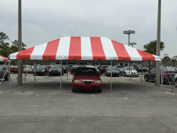 Vehicle parked beneath large striped tent.