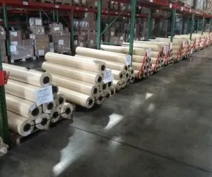 Rolls of paper stacked in warehouse aisle.