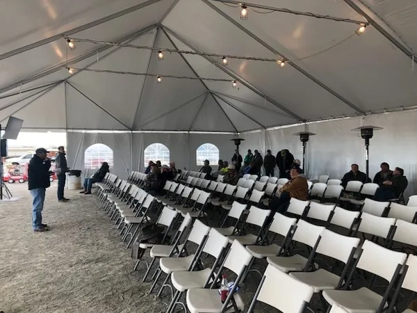 Event tent with empty chairs and attendees