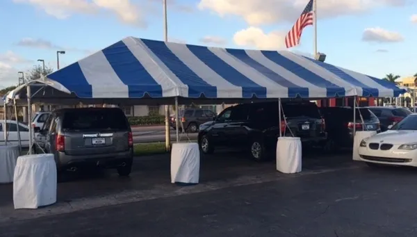 Large blue-striped pavilion sheltering vehicles