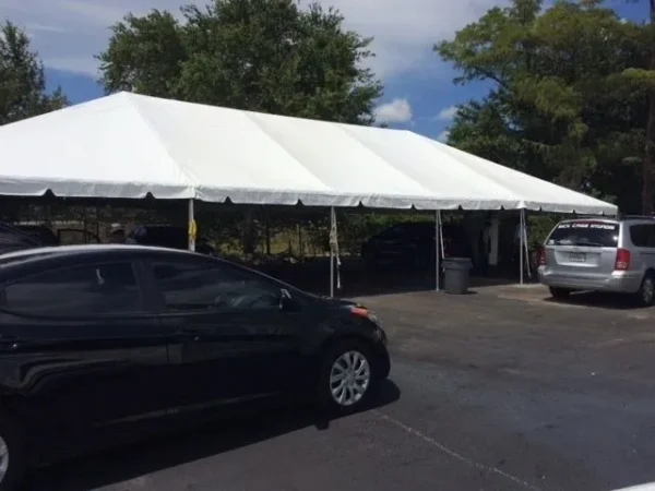 Outdoor event tent with vehicles nearby